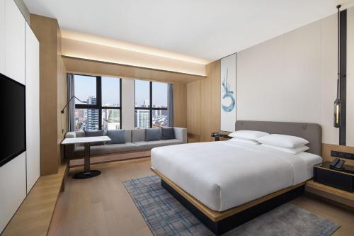 ein Schlafzimmer mit einem großen weißen Bett und einem Sofa in der Unterkunft Fairfield by Marriott Huai'an Downtown in Huai'an