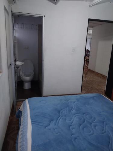 a bedroom with a blue bed in a room with a toilet at Los balcones lll in Medellín