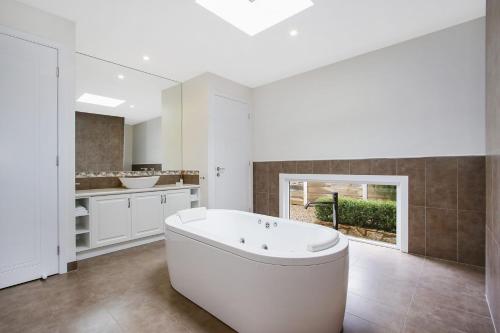 La salle de bains blanche est pourvue d'une baignoire et d'un lavabo. dans l'établissement Bright Bliss Luxury Guesthouse, à Bright