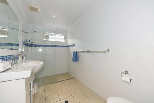 a white bathroom with a sink and a toilet at Aqua Vincentia - Belle Escapes Jervis Bay in Vincentia