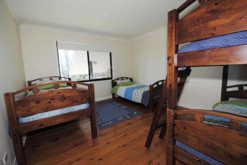 a room with three bunk beds and a window at Beachfront Unit - Belle Escapes Jervis Bay in Vincentia