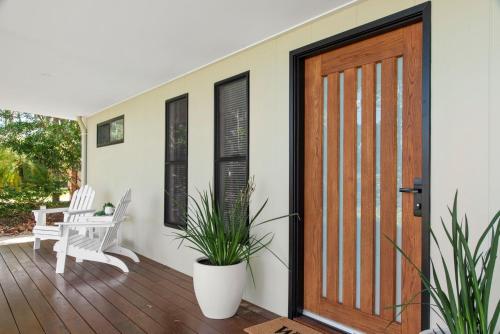 a front door of a house with two potted plants at Edge Water - Belle Escapes Jervis Bay in St Georges Basin