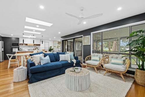 a living room with a blue couch and a table at Edge Water - Belle Escapes Jervis Bay in St Georges Basin