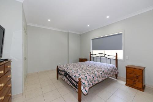 a bedroom with a bed and a dresser and a window at Paradise Beach House - Belle Escapes Jervis Bay in Sanctuary Point