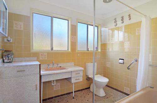 a bathroom with a toilet and a sink and a shower at Pipers Run - Belle Escapes Jervis Bay in Vincentia