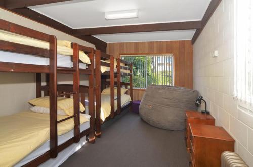 a room with three bunk beds and a desk at Pipers Run - Belle Escapes Jervis Bay in Vincentia
