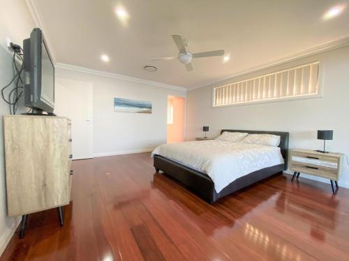 a bedroom with a bed and a flat screen tv at Pardesa A Little Piece Of Paradise - Belle Escapes Jervis Bay in St Georges Basin
