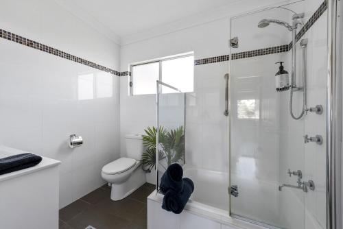 a white bathroom with a shower and a toilet at Soul Beach House - Belle Escapes Jervis Bay in Vincentia