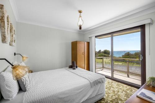 a bedroom with a bed and a large window at Nelsons Beach House - Belle Escapes Jervis Bay in Vincentia