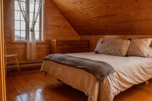 - une chambre avec un lit dans une cabane en rondins dans l'établissement Les Chalets Tourisma - Maison de campagne avec spa - La Campagnarde, à Saint-Raymond