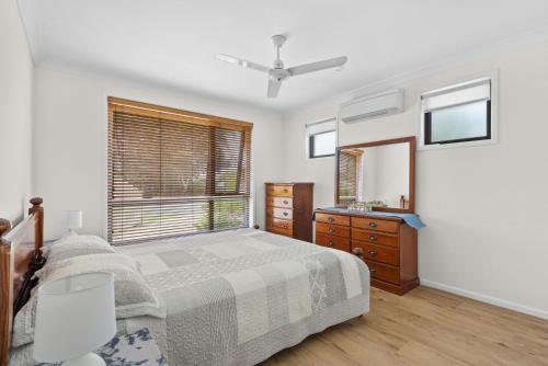 a bedroom with a bed and a dresser and a window at Villa Serene - Belle Escapes Jervis Bay in Vincentia