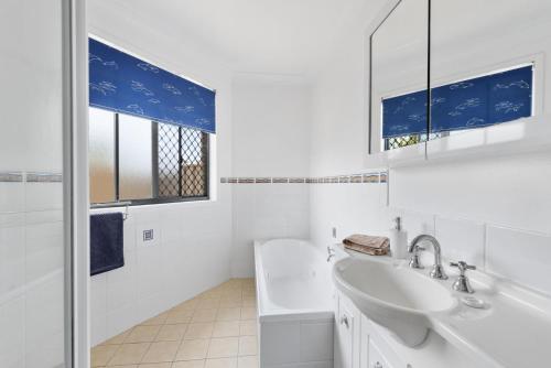 a white bathroom with a sink and a mirror at Villa Serene - Belle Escapes Jervis Bay in Vincentia