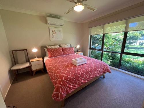 a bedroom with a bed with a pink comforter and a window at Magnolia on Toorak in Bright