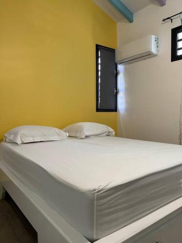 a large white bed in a room with a window at Villa les pastels in Le Gosier