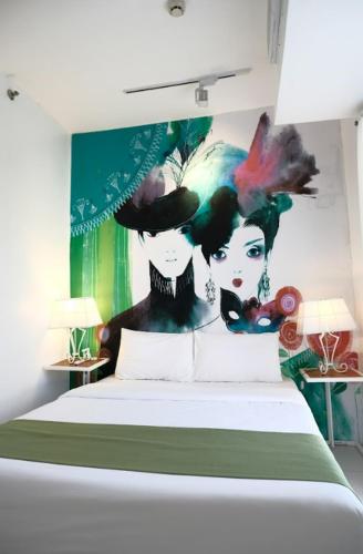 a bedroom with a painting of two women on the wall at La Bella Boutique Hotel in Tagaytay