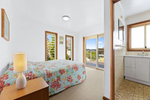a bedroom with a bed and a bathroom with a sink at 3 Bay Lane in Narooma