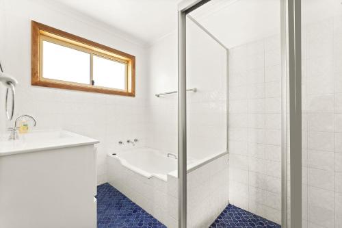 a white bathroom with a tub and a sink at 3 Bay Lane in Narooma