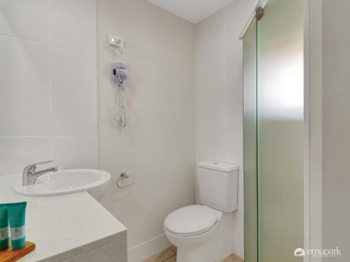 a white bathroom with a toilet and a sink at Studio 20 ENDEAVOUR INN in Emu Park