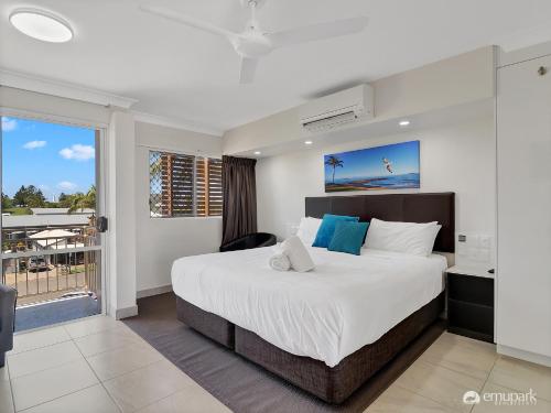 a bedroom with a large bed and a balcony at Studio 20 ENDEAVOUR INN in Emu Park