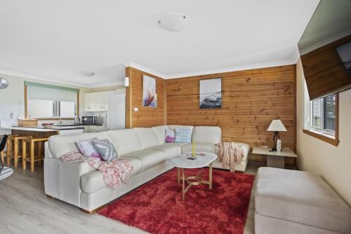 a living room with a white couch and a red rug at Waters Edge - Belle Escapes Jervis Bay in Erowal Bay