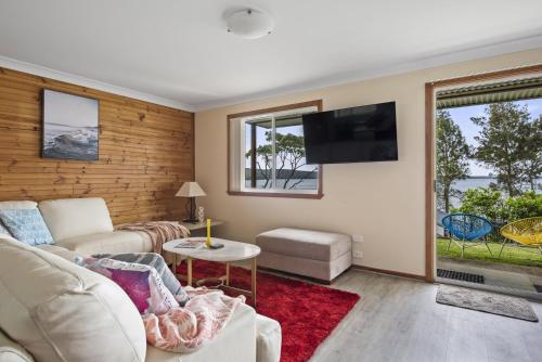 a living room with a couch and a tv at Waters Edge - Belle Escapes Jervis Bay in Erowal Bay