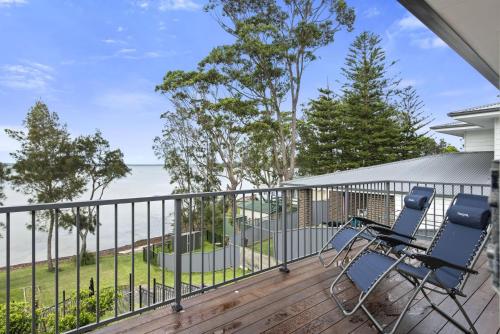 a balcony with two chairs and a view of the ocean at Waters Edge - Belle Escapes Jervis Bay in Erowal Bay