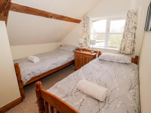 two beds in a room with a window at The Smithy in Llandyfrydog