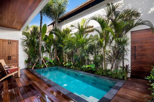 una piscina en medio de una casa con palmeras en Nusantara Loft Rote by Alfred in Bali, en Canggu