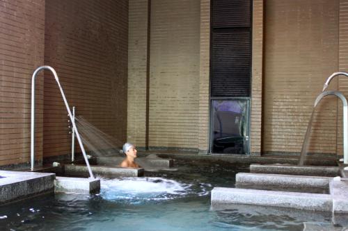 a man in a swimming pool with two faucets at Golden Tulip Zhong Xin Hotel Taichung in Taichung