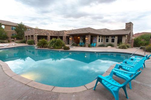 a swimming pool with blue chairs in front of a house at H7-Heavenly-Ground Floor 3-bedroom Hillside View in Hurricane