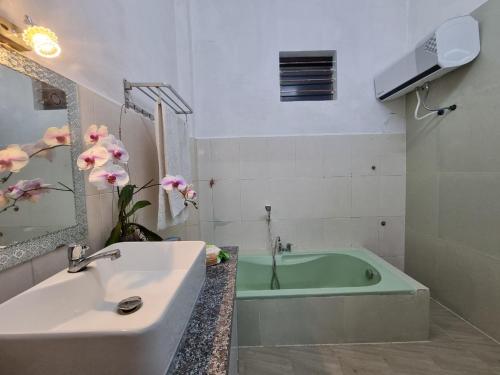 y baño con bañera y lavamanos. en Katie's homestay en Ðông Mỹ (2)