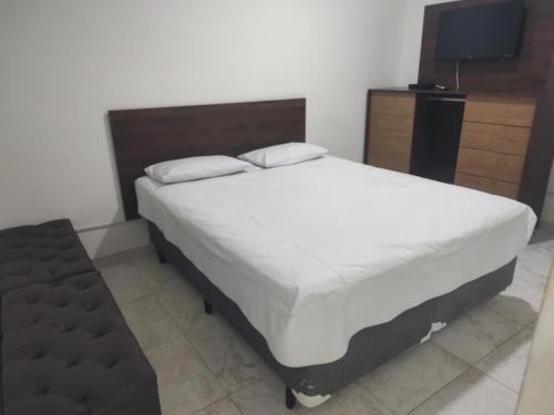 een slaapkamer met een groot bed en een televisie bij Apartamento mobiliado prédio frente ao mar in São Vicente