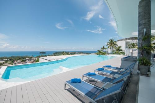 a swimming pool with lounge chairs and the ocean at The View Phuket in Kata Beach