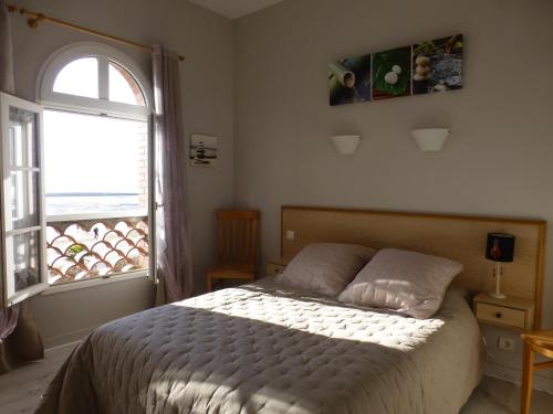 um quarto com uma cama e uma grande janela em Appartement bord de plage Tranche s/mer em La Tranche-sur-Mer