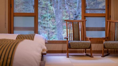 a room with two chairs and a bed and a window at Oyado Tsuruya in Matsumoto
