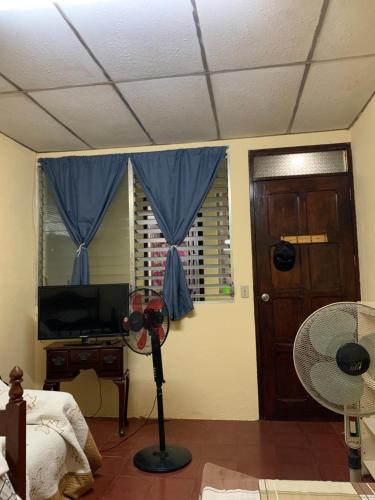 a room with a bedroom with a fan and a window at Habitación en casa Familiar in León