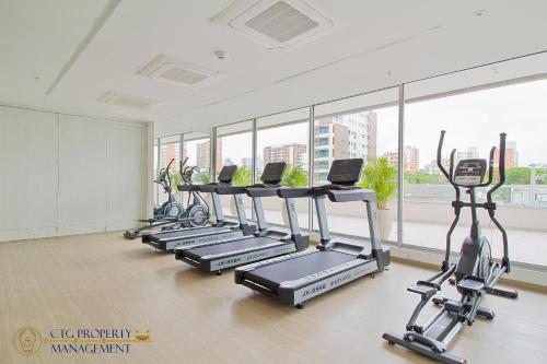 una fila de cintas de correr en un gimnasio con ventanas en Distrito 90 - Estudios y Apartamentos para vacaciones y viajes de negocio, en Barranquilla