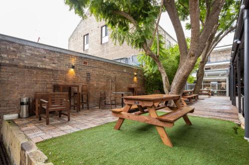een patio met banken, tafels en een boom bij The Village Surry Hills in Sydney