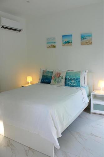 a white bed in a white room with two lamps at Villa Luce in Las Terrenas