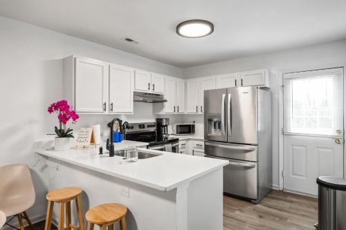 a kitchen with white cabinets and a stainless steel refrigerator at DTGem-SelfCheckin-RainShower-300M-Parking-Walkable in Raleigh