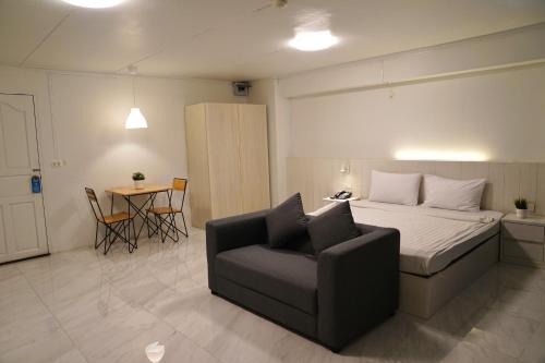 a bedroom with a bed and a chair and a table at View Place Hotel & Residence in Bangkok
