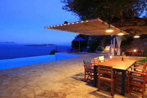 a wooden table and chairs on a patio at night at Villa Evalin - Pretty Villa Like at Home for Unforgettable Holidays in Sivota
