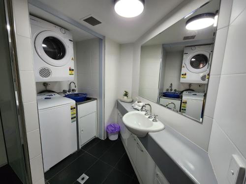 a white bathroom with a sink and a mirror at Fairways Golf & Beach Retreat Bribie Island in Woorim