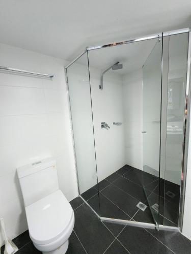 a bathroom with a toilet and a glass shower at Fairways Golf & Beach Retreat Bribie Island in Woorim