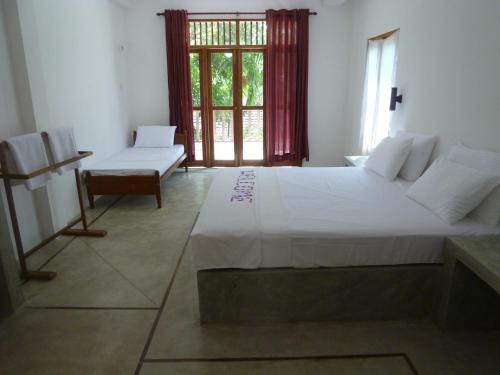 a bedroom with a large white bed and a window at Villa Unawatuna in Unawatuna