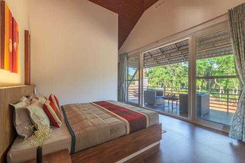 a bedroom with a bed and a large window at Coffee & Mist Luxury Villa- Comp Breakfast, Pool, Lounge, and Coffee Estate by StayVista in Madikeri