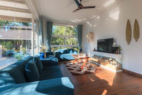 a living room with a blue couch and a table at 5BR Coffee & Mist Luxury Villa-High Speed Wifi- Comp Breakfast, Pvt Pool, and Coffee Estate Virajpet in Madikeri