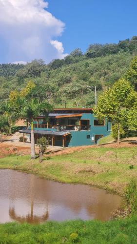 a blue house with a pond in front of it at Espaço Canto in Santo Antônio do Pinhal