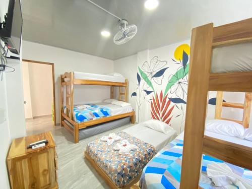 Cette chambre comprend 3 lits superposés et une table. dans l'établissement HOSTAL LAS FLORES, à Capurganá
