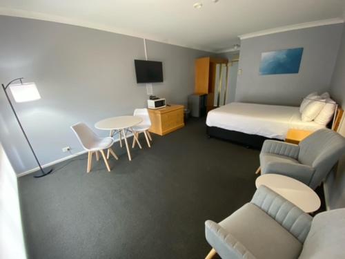 a hotel room with a bed and a table and chairs at Old Maitland Inn - Rutherford in Maitland